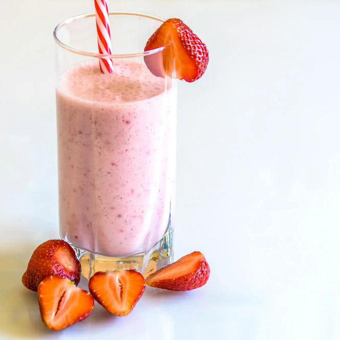 Glass of strawberry smoothie with fresh strawberries and striped straw