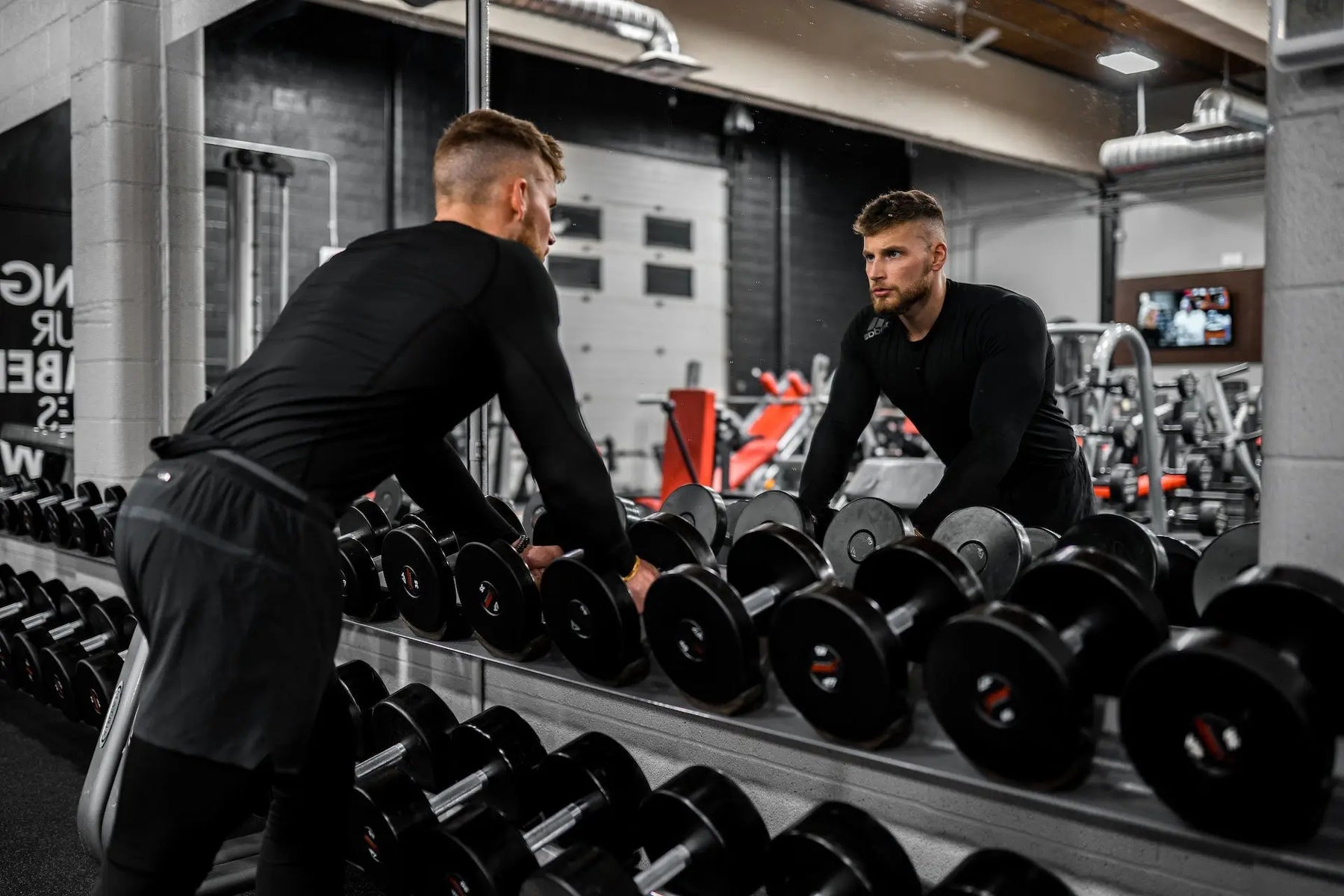 man in black pants and black long sleeve shirt carrying black dumbbells