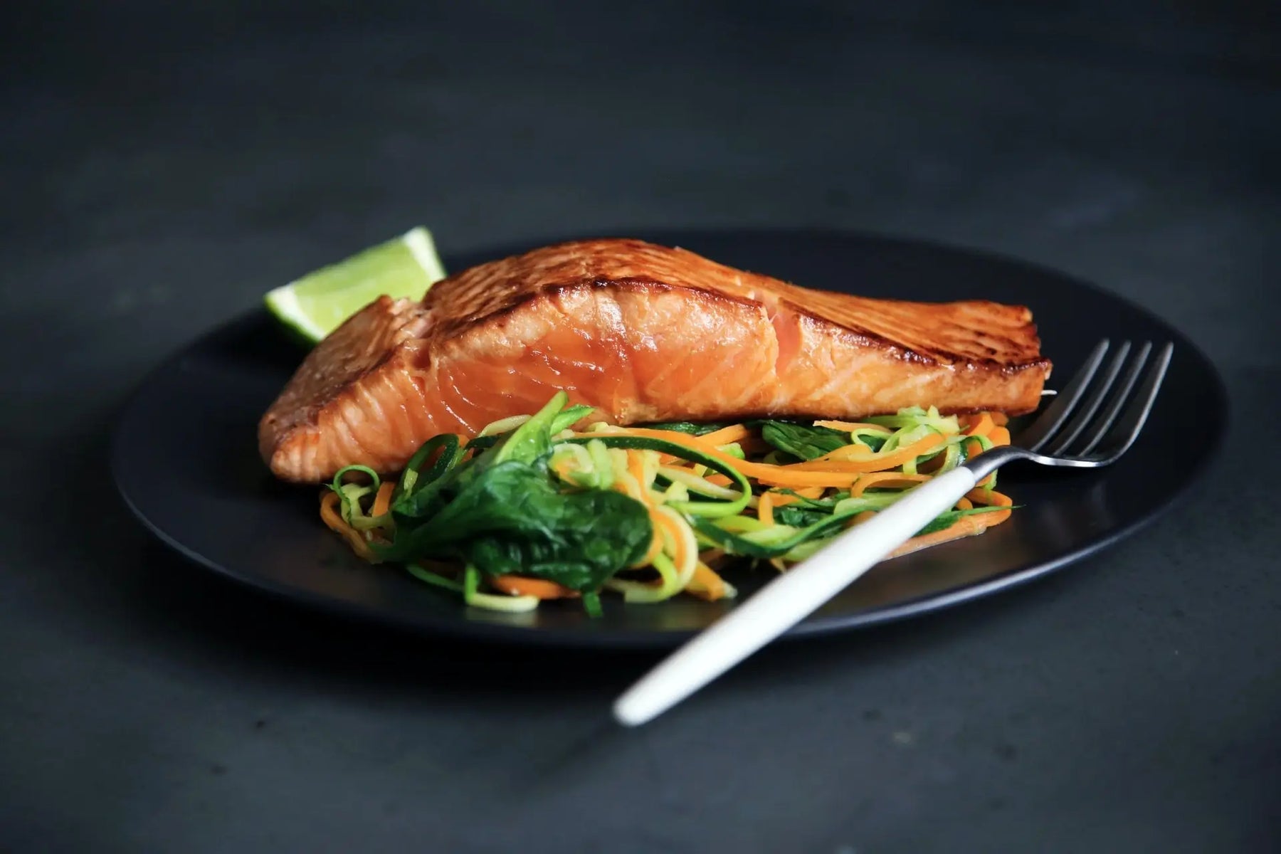 Grilled fish, cooked vegetables and fork on plate